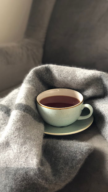 A warm cup of coffee nestled in a soft gray blanket, creating a cozy atmosphere. HD phone wallpaper