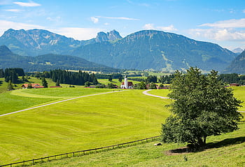 Beautiful rural landscape with lush fields, mountains, and quaint village in sunny weather. HD wallpaper