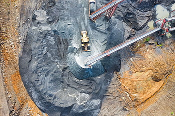 Aerial view of a large industrial mining site with heavy machinery and conveyor belts in operation. HD wallpaper