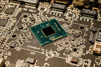 Detailed view of a microchip on a printed circuit board, showcasing electronic components. HD wallpaper