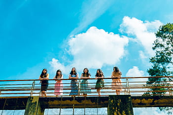 A group of young women standing on a bridge under a bright summer sky, enjoying leisure time. HD wallpaper