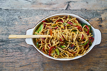 Tasty stir-fried noodles with fresh vegetables and sesame seeds, perfect for a healthy meal. HD wallpaper