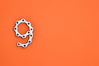 A metal chain shaped like the number nine against a vibrant orange background with copy space. HD wallpaper
