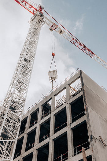 High-rise building construction with a tower crane against a cloudy sky. HD phone wallpaper