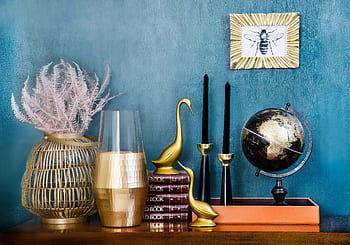 Stylish home decor arrangement including a globe, books, candles, and vases on a blue backdrop. HD wallpaper