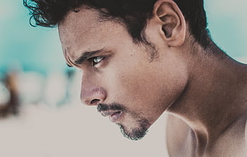 A close-up portrait of a young man looking thoughtfully into the distance. HD wallpaper