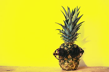 A stylish pineapple wearing sunglasses against a bright yellow background. HD wallpaper