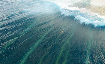 Breathtaking aerial shot of a surfer navigating the waves in Malé, Maldives. HD wallpaper