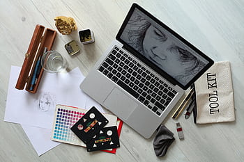 Top view of a creative workspace with a laptop, sketch supplies, and color palette. HD wallpaper