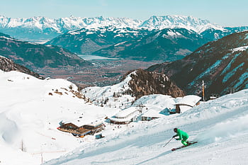 A skier enjoying the snowy slopes with stunning views of the Kaprun Alps in Austria. HD wallpaper