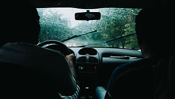 Two people drive through rainy São Paulo streets, wet windshield and raindrops visible. HD wallpaper