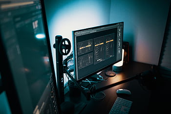 A stylish modern workspace with dual monitors displaying design software in a dimly lit room. HD wallpaper