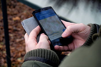 Close-up of hands using a map app on a smart outdoors, showcasing GPS navigation. HD wallpaper