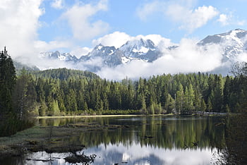 Tranquil scene of the High Tatras mountains reflected in a forest lake with calm waters. HD wallpaper