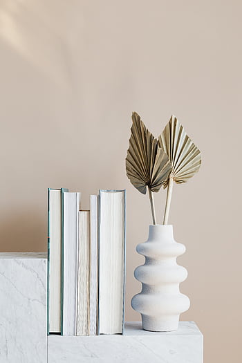 Elegant minimalist bookshelf decor featuring a stylish vase with dried leaves and neatly arranged books. HD phone wallpaper