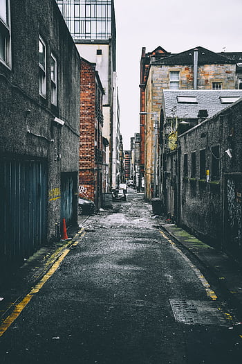 Quiet urban alley with parked cars between old brick buildings, showcasing city life. HD phone wallpaper