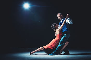 Elegant couple performing tango under a dramatic spotlight, showcasing passion and grace. HD wallpaper