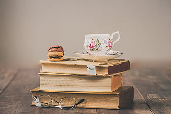 Elegant setup of floral teacup with macarons on a stack of vintage books. HD wallpaper