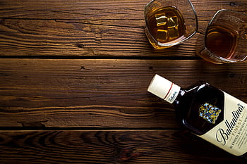 Top view of whiskey bottle and glasses on rustic wooden table, ideal for bar or celebration themes. HD wallpaper