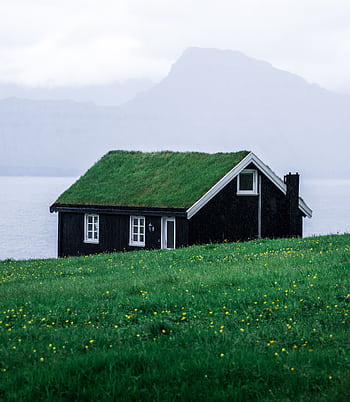 Charming black wooden house with a grass roof in the tranquil Faroe Islands landscape. HD phone wallpaper