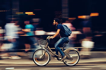 A cyclist swiftly rides through an urban street, capturing the essence of city life and motion. HD wallpaper