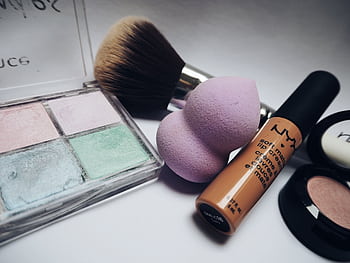 A flat lay showcasing various makeup essentials including brushes, sponges, and cosmetics. HD wallpaper