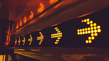 A series of glowing arrow signs in a city environment, indicating direction at night. HD wallpaper