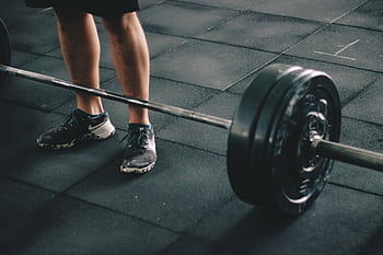 Close-up of a man deadlifting a heavy barbell in an indoor gym setting. HD wallpaper