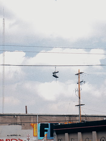 Street view of sneakers hanging on power lines against cloudy sky in Denver. HD phone wallpaper