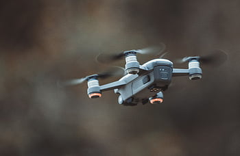 A detailed close-up of a drone flying in an outdoor setting, showcasing its design and technology. HD wallpaper