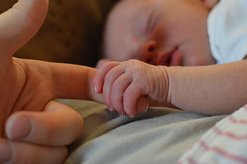 A heartwarming close-up of a newborn baby gently holding an adult's finger, symbolizing love and connection. HD wallpaper