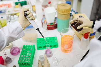 Scientists conducting an experiment with chemicals and tools in a modern lab setting. HD wallpaper