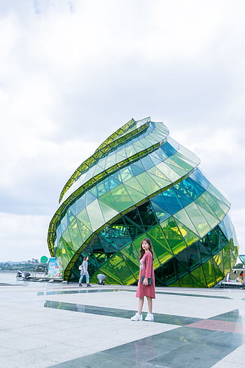 A young Asian woman poses in front of the iconic glass structure in Da Lat, Vietnam, on a sunny day. HD phone wallpaper