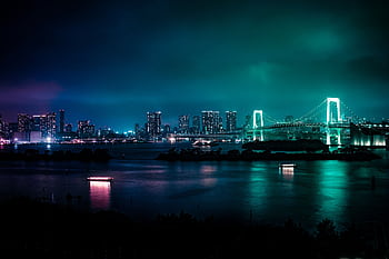 Illuminated Tokyo skyline featuring the iconic Rainbow Bridge at night, reflected in calm bay waters. HD wallpaper