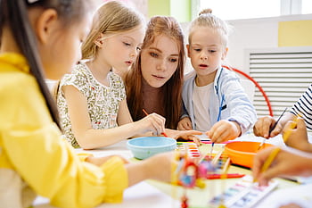 Kids in a classroom painting with watercolor, guided by a teacher, fostering creativity and teamwork. HD wallpaper