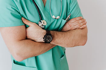 Close-up of a male doctor in scrubs with crossed arms and stethoscope on white background. HD wallpaper