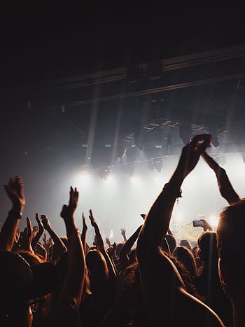 Vibrant concert atmosphere with cheering crowd under spotlights and lively music. HD phone wallpaper