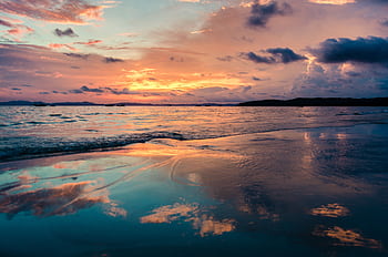 Stunning sunset over the ocean with vibrant reflections on a tranquil beach. HD wallpaper