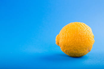 Vivid close-up of a ripe lemon against a bright blue background, emphasizing freshness. HD wallpaper
