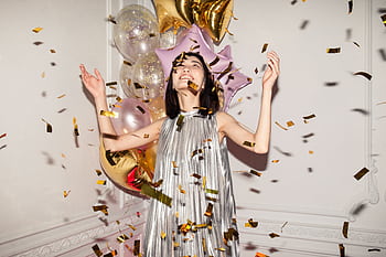 Joyous indoor celebration with balloons and confetti featuring a stylish young woman. HD wallpaper