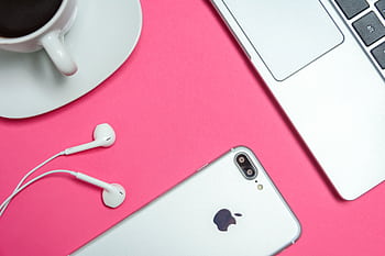 A modern workspace with laptop, smart, and coffee cup on a vibrant pink background. HD wallpaper