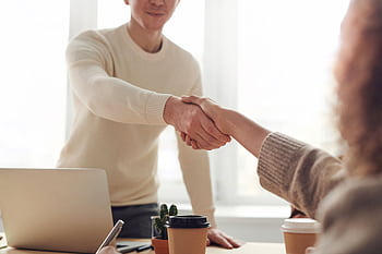 Close-up of professionals shaking hands over coffee in a modern office. HD wallpaper