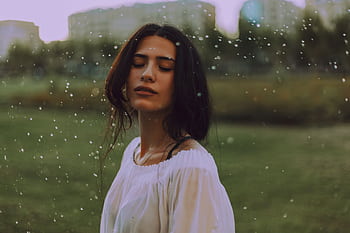 Serene portrait of a young woman enjoying the outdoors, with gentle rain falling. HD wallpaper