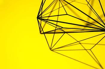 Creative geometric structure casting intricate shadows on a vibrant yellow background. HD wallpaper