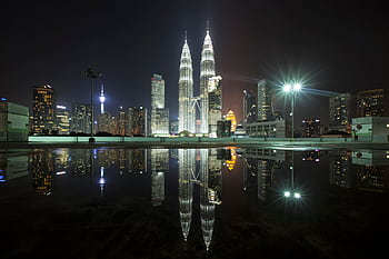 Beautiful view of Kuala Lumpur's skyline featuring the iconic Petronas Towers at night with city lights and reflections. HD wallpaper