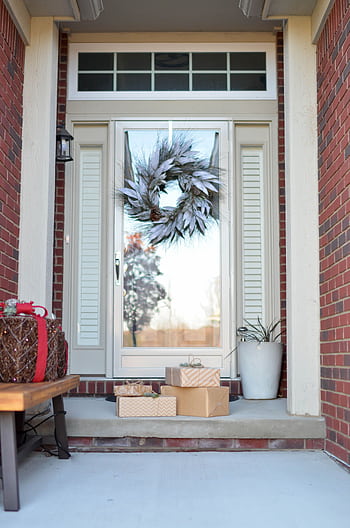 An inviting front door adorned with a holiday wreath and wrapped gifts, perfect for the festive season. HD phone wallpaper