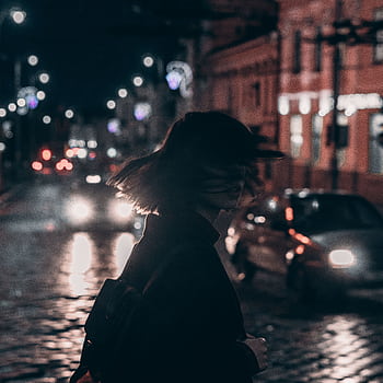 Silhouette of a woman walking on a bustling city street at night with blurred car lights. HD phone wallpaper