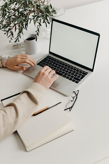 A clean and modern workspace featuring a laptop, houseplant, and notebook. HD phone wallpaper