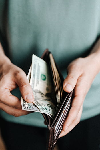 Close-up of hands holding a wallet with cash, depicting financial management. HD phone wallpaper