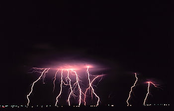 A striking display of lightning illuminating the night sky over a city landscape. HD wallpaper